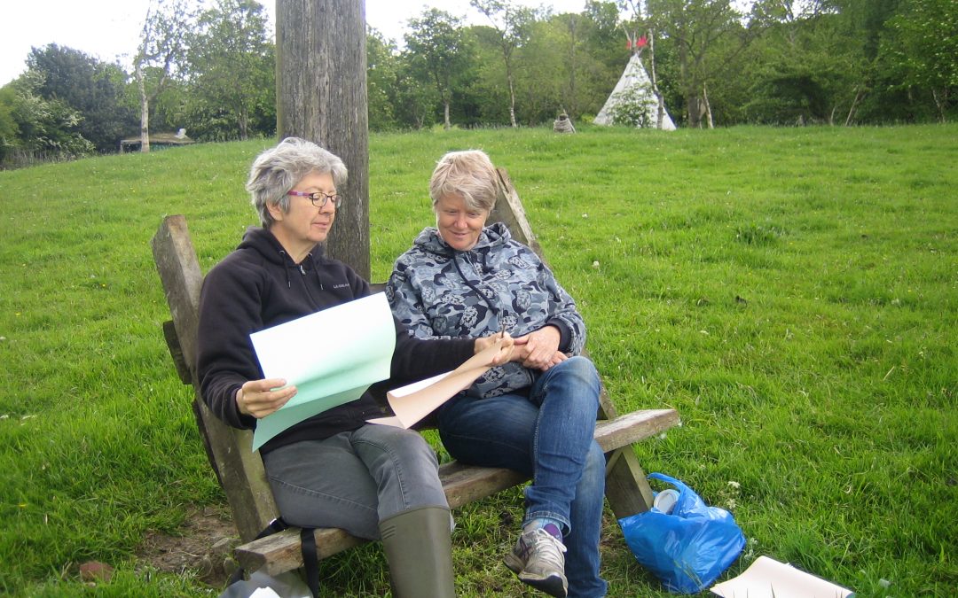 Laura and Uddyotani discussing courses on a bench in an outdoors green space.